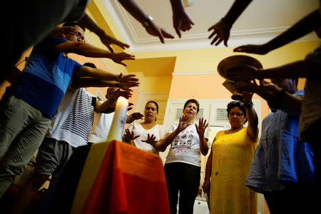 Activists supporting the lesbian, gay, bisexual and transgender community (LGBT) stretch out their hands during a religious service in Havana, Cuba, October 15, 2018. REUTERS/Alexandre Meneghini