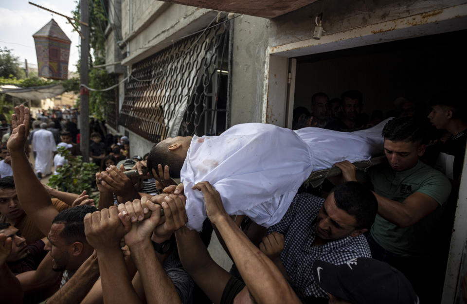 Mourners carry the body of Palestinian Tamim Hijazi, who was killed in an Israeli air strike, during his funeral in Khan Yunis in the southern Gaza Strip, Saturday, Aug. 6, 2022. Israeli jets pounded militant targets in Gaza as rockets rained on southern Israel, hours after a wave of Israeli airstrikes on the coastal enclave killed at least 11 people, including a senior militant and a 5-year-old girl. The fighting began with Israel's dramatic targeted killing of a senior commander of the Palestinian Islamic Jihad continued into the morning Saturday, drawing the sides closer to an all-out war. (AP Photo/Yousef Masoud)