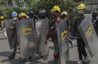 Anti-coup protesters with makeshift shields walk to take positions in Mandalay, Myanmar, Tuesday, March 9, 2021. Demonstrators in Myanmar's biggest city came out Monday night for their first mass protests in defiance of an 8 p.m. curfew, seeking to show support for an estimated 200 students trapped by security forces in a small area of one neighborhood. (AP Photo)