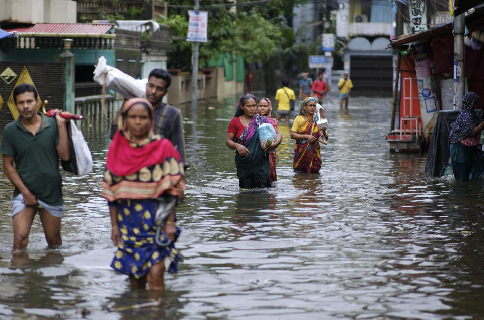 People wade through flood waters in Sylhet, Bangladesh, Monday, June 20, 2022. Floods in Bangladesh continued to wreak havoc Monday with authorities struggling to ferry drinking water and dry food to flood shelters across the country’s vast northern and northeastern regions. (AP Photo/Mahmud Hossain Opu)