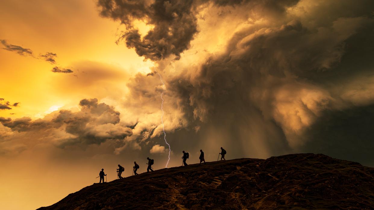  Hikers on the storm at sunset, Catbells Mountain, Lake District. UK. 