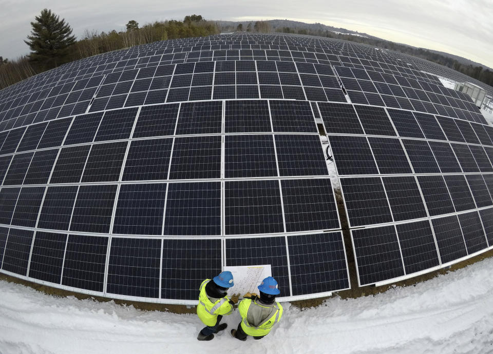 Electricians Zach Newton and Bryan Driscoll consult a wiring schematic while installing solar panels at the 38-acre BNRG/Dirigo solar farm, Thursday, Jan. 14, 2021, in Oxford, Maine. President Joe Biden wants to change the way the U.S. uses energy by expanding renewables, but faces several challenges.. (AP Photo/Robert F. Bukaty)