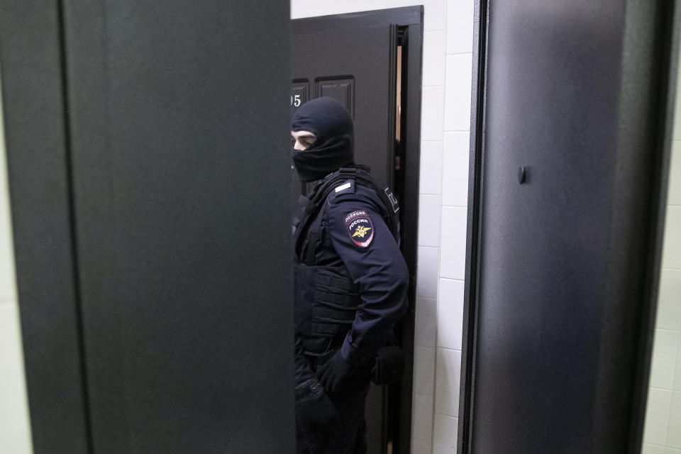 A police officer stands in front of a door of the apartment of jailed opposition leader Alexei Navalny in Moscow, Russia, Wednesday, Jan. 27, 2021. Police are searching the Moscow apartment of jailed Russian opposition leader Alexei Navalny, another apartment where his wife is living and two offices of his anti-corruption organization. Navalny's aides reported the Wednesday raids on social media. (AP Photo/Pavel Golovkin)