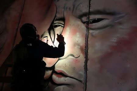 An Australian graffiti artist works on his mural depicting U.S. President Donald Trump and Israeli Prime Minister Benjamin Netanyahu on the controversial Israeli barrier in the West Bank city of Bethlehem October 28, 2017. Picture taken October 28, 2017. REUTERS/Ammar Awad