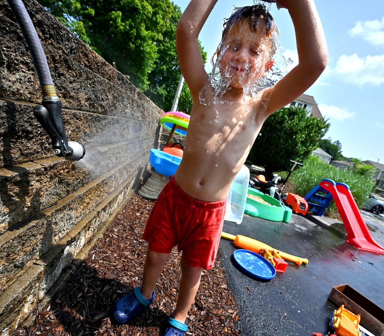 Nico Labb, who turns 4 in September, dumps a pile of water over his head while cooling off with a garden hose with his grandmother, Noni, on Hamilton Street Wednesday.