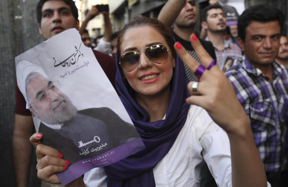 A female supporter of Iranian presidential candidate Hassan Rouhani flashes a victory sign as she holds his poster during a celebration gathering in Tehran, Iran, Saturday, June 15, 2013. (AP Photo/Vahid Salemi)