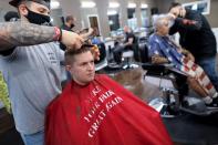 Aaron Schumacher, 33, of Staten Island has his hair cut at Craig & Pop's Barbershop while wearing a salon cape with a parody of U.S. President Donald Trump's "Make America Great Again" phrase on Staten Island in New York City