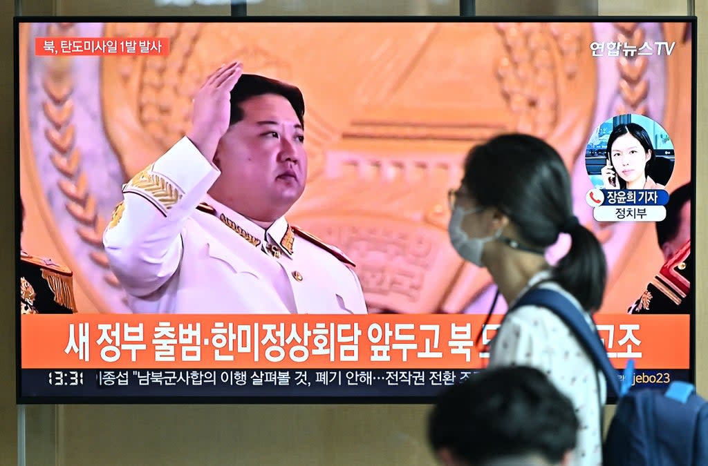 A woman walks past a television screen showing a news broadcast with file footage of North Korean leader Kim Jong Un, at a railway station in Seoul (AFP via Getty)