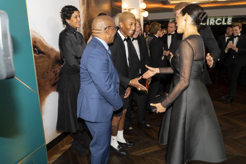 A photo of Britain's Prince Harry, Duke of Sussex and Britain's Meghan, Duchess of Sussex (R) greeting US singer Pharrell Williams (C) as they arrive to attend the European premiere of the film The Lion King in London on July 14, 2019.