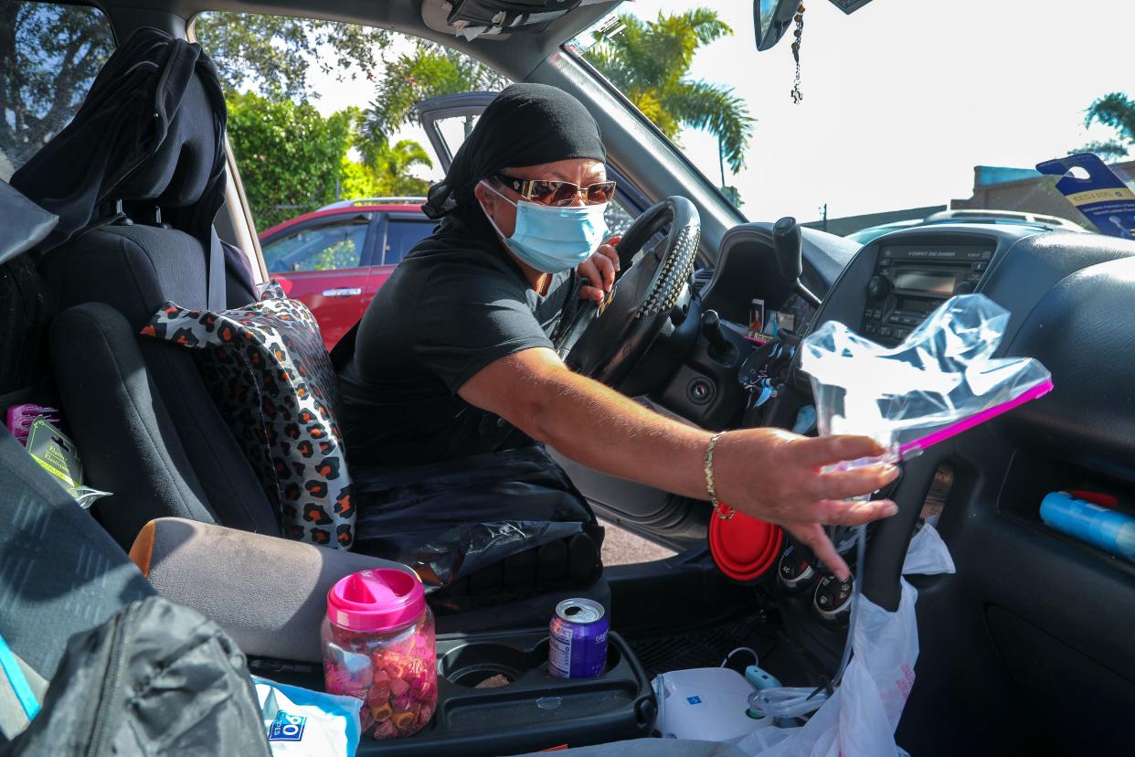 Marie, who is homeless and lives in her car with her service dog Michelle, reaches for her nebulizer equipment before entering St. Ann's Place in West Palm Beach where she will receive a nebulizer treatment.