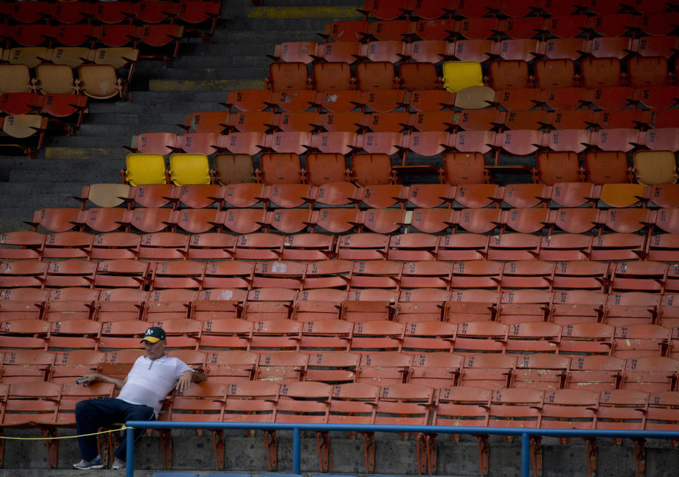 In this Oct. 12, 2018 photo, a lone baseball fan waits for the season's opening baseball game between Leones de Caracas and Tiburones de la Guaira in Caracas, Venezuela. Some baseball fans avoid the ballpark for fear of getting mugged or because they don't know how they'll get home amid a nationwide transportation crisis. (AP Photo/Fernando Llano)