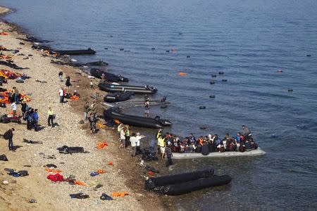 Refugees and migrants arrive on an overcrowded dinghy on a beach full of abandoned dinghies and lifejackets, on the Greek island of Lesbos, after crossing a part of the Aegean Sea from the Turkish coast, October 5, 2015. REUTERS/Dimitris Michalakis