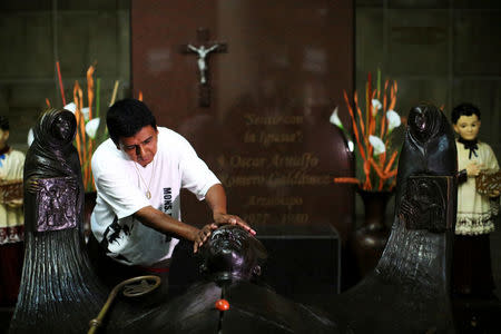 FILE PHOTO: A man prays as he waits for the newly elevated Cardinal Gregorio Rosa Chavez at the grave of Mons. Oscar Arnulfo Romero upon his return at the Metropolitan Cathedral in San Salvador, El Salvador, July 4, 2017. REUTERS/Jose Cabezas/File Photo