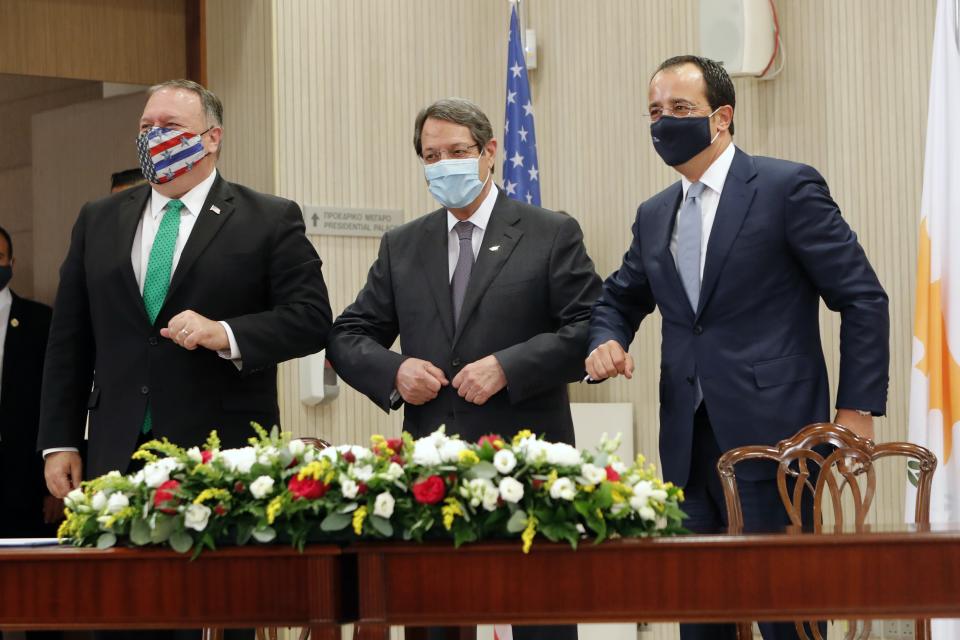 U.S. Secretary of State Mike Pompeo, left, Cypriot President Nicos Anastasiades, center, and Cypriot Foreign Minister Nikos Christodoulides touch elbows during their meeting at the Presidential Palace in Nicosia, Cyprus, Saturday, Sept. 12, 2020. Pompeo's lightning visit to Cyprus aimed to de-escalate a confrontation between Greece and Turkey over energy reserves in east Mediterranean waters and to affirm Washington's continued engagement in the tumultuous region four days after Russian Foreign Minister Sergey Lavrov pitched Moscow's offer to help ease tensions during his trip to the island nation. (AP Photo/Petros Karadjias, Pool)