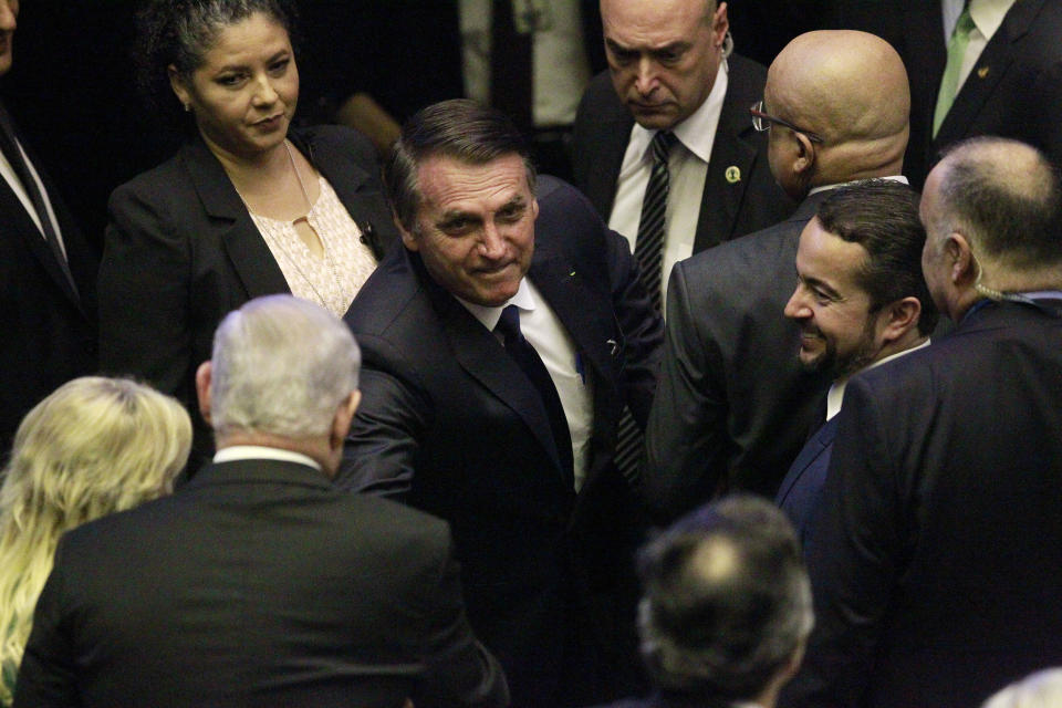 El presidente de Brasil, Jair Bolsonaro, en el centro, saluda a los invitados a su ceremonia de investidura, en el plenario del Congreso Nacional Brasileño, el martes 1 de enero de 2019 en Brasilia. (Foto AP/Raimundo Pacco)