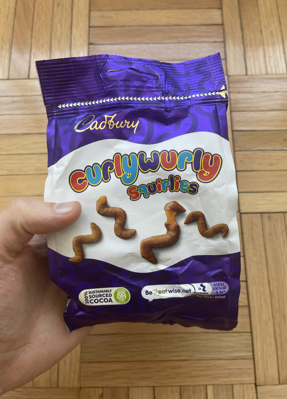 Hand holding a bag of Curly Wurly Squirlies