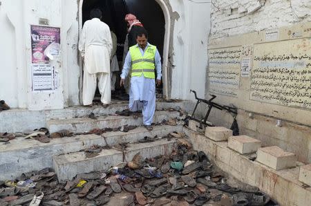A rescue worker steps outside where victims' shoes are scattered after an explosion in a Shi'ite mosque in Shikarpur, located in Pakistan's Sindh province January 30, 2015. REUTERS/Amir Hussain