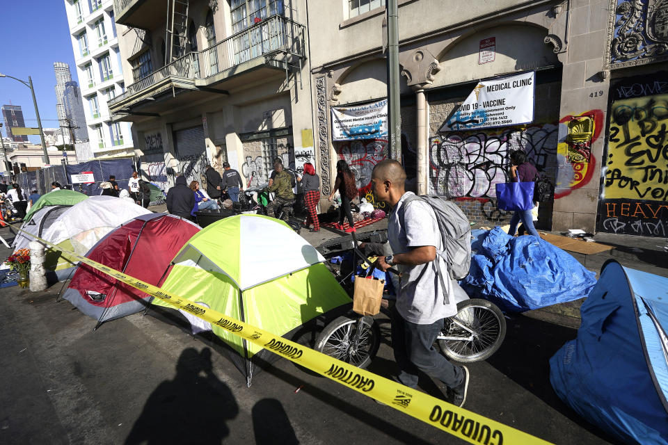 FILE - People line up along temporary tents to partake in a free Thanksgiving meal provided by the Union Rescue Mission as the Los Angeles Skid Row district annual feast hosts thousands of homeless and others in need, in downtown Los Angeles on Nov. 24, 2022. Democratic leaders in major U.S. cities are finding themselves politically squeezed when it comes to addressing homelessness. Some hope L.A.'s newly elected Mayor Karen Bass will make good on her campaign promise to move people out of tents and cardboard shanties and eventually into permanent housing. (AP Photo/Damian Dovarganes, File)