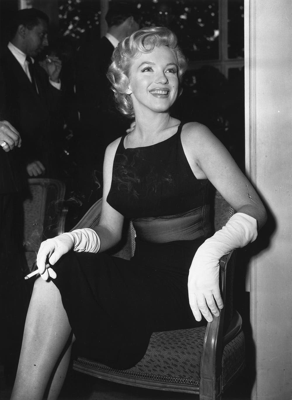 Marilyn Monroe wearing a sheer black dress and holding a cigarette.