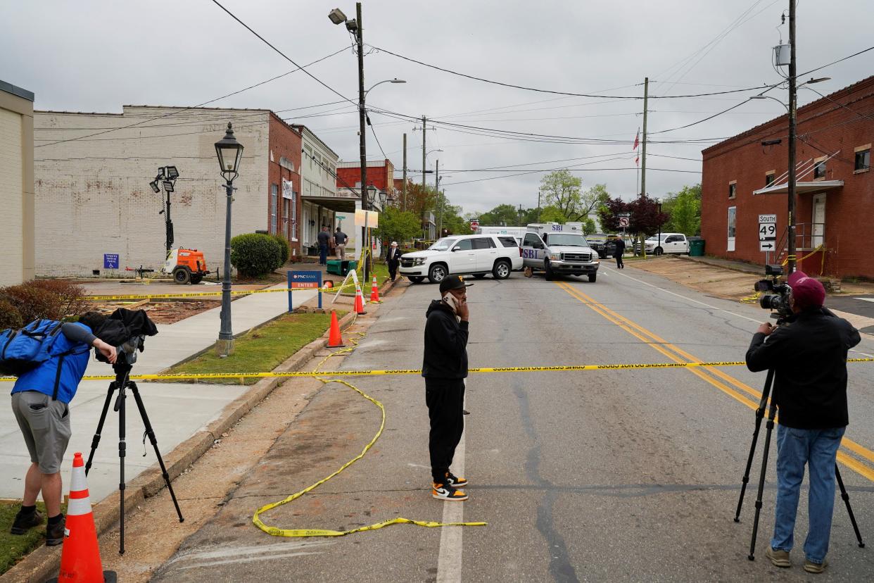 Community members and media stand near the crime scene (16 April 2023) (REUTERS)