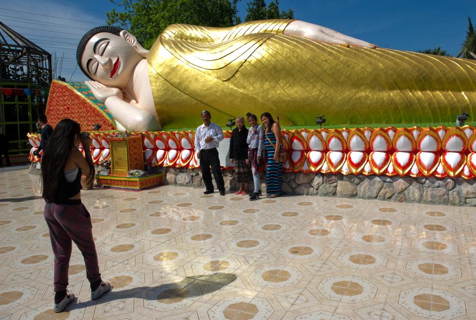 (4/19/15) People have their pictures taken in front of the giant statue of a reclining Buddha at the Wat Dhammararam Buddhist Temple during the Cambodian New Years celebration at the temple in Stockton.    