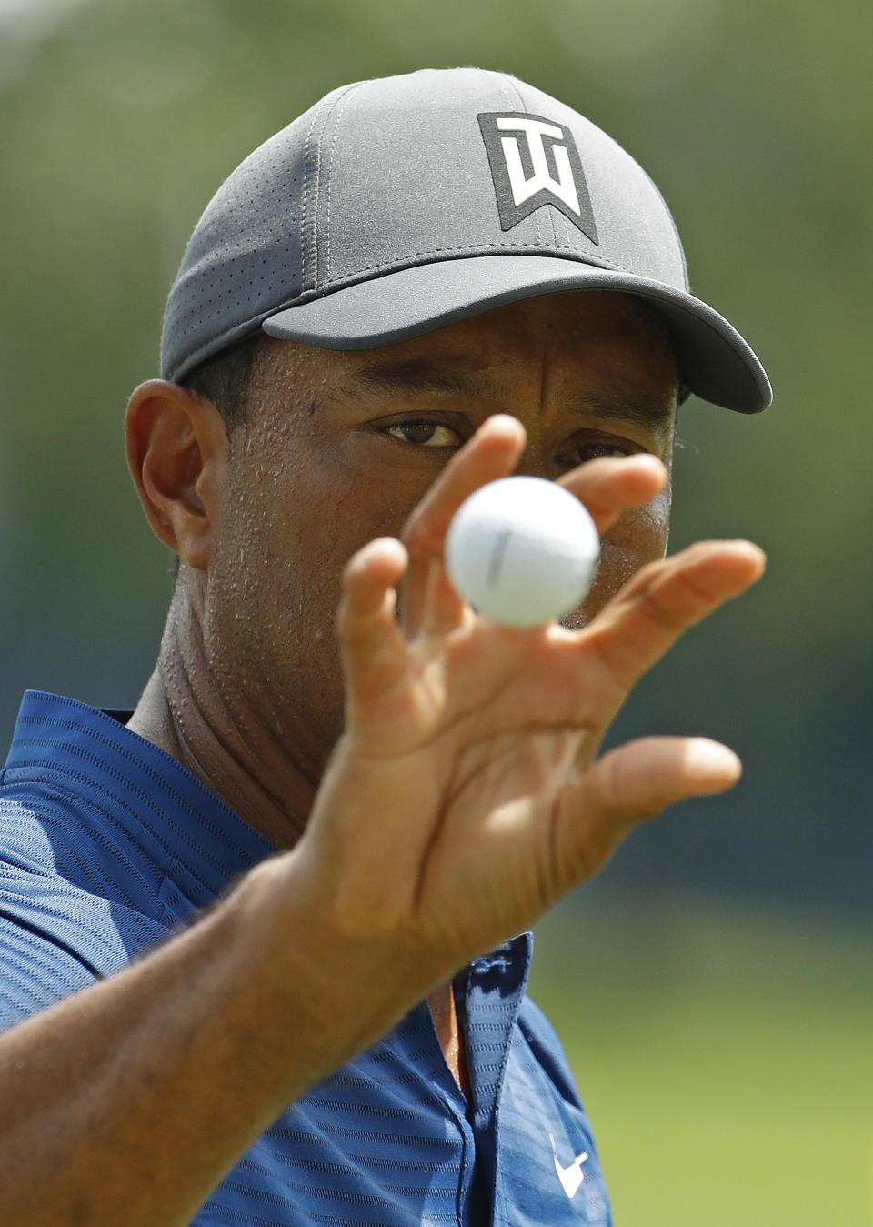 Tiger Woods catches a golf ball while hitting on the driving range during a practice round for the PGA Championship golf tournament at Bellerive Country Club, Wednesday, Aug. 8, 2018, in St. Louis. (AP Photo/Charlie Riedel)