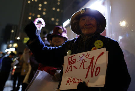 A protester holding a banner rises her fist during an anti-nuclear rally in front of the headquarters of Tokyo Electric Power Co (TEPCO), the operator of the tsunami-crippled Fukushima Daiichi nuclear plant, a day before the five-year anniversary of the disaster, in Tokyo, Japan, March 10, 2016. The banner reads in Japanese "No nuclear power plant". REUTERS/Yuya Shino