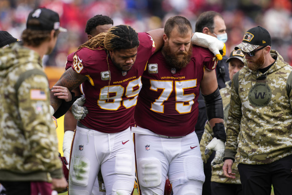 Washington Football Team defensive end Chase Young (99) is helped off the field by guard Brandon Scherff (75) after an injury during the first half of an NFL football game against the Tampa Bay Buccaneers, Sunday, Nov. 14, 2021, in Landover, Md. (AP Photo/Nick Wass)