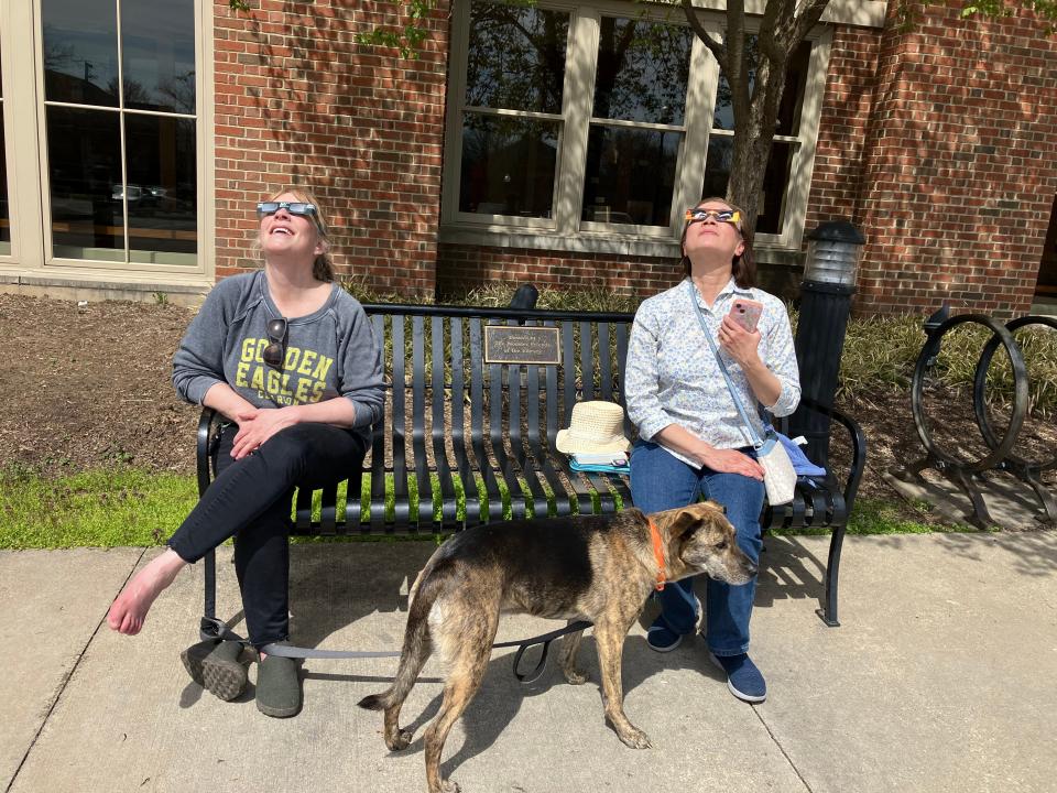 As the 1:58 p.m. onset of the eclipse began, Judi Costanza, from the Pittsburgh area, and Diep Nguyen, from Maryland, looked through their glasses from a bench outside the library.