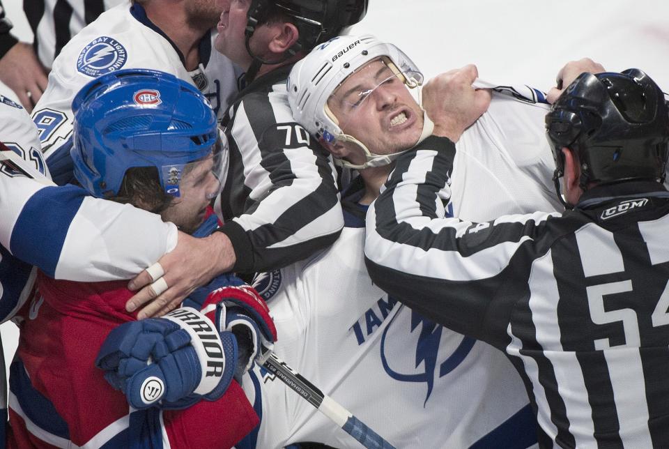 Tampa Bay Lightning's Ryan Callahan (24) is held back by a linesman as he grapples with Montreal Canadiens' David Desharnais, left, during second period NHL Stanley Cup playoff action in Montreal, Tuesday, April 22, 2014. (AP Photo/The Canadian Press, Graham Hughes)