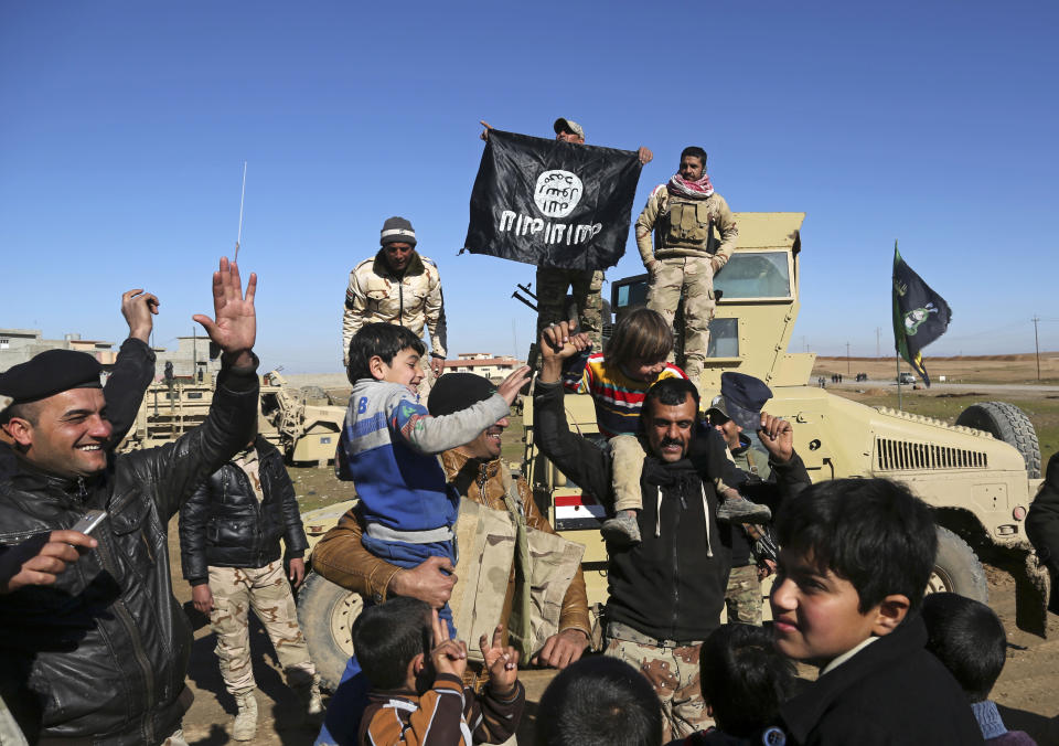 FILE -- In this Jan. 24, 2017 file photo, Iraqi army soldiers celebrate with residents of neighborhoods retaken by Iraqi security forces from Islamic State militants as they hold upside down a flag of the IS group, in the eastern side of Mosul, Iraq. The eastern half of Mosul was declared “fully liberated” in January, but nearly three months later the streets are filled with rubble, there’s no electricity or water, and civil servants are not being paid. Anger at the Iraqi government, which was a key factor in the Islamic State takeover of the country’s second largest city in 2014, is starting to return. (AP Photo/ Khalid Mohammed, File)