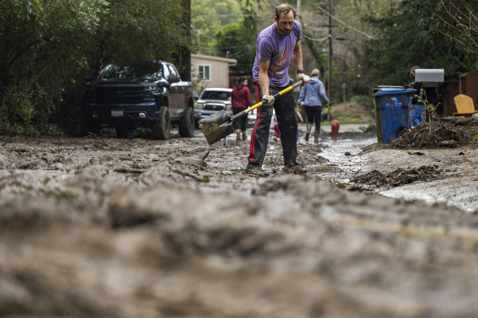 Matt O'Brien shovels mud from a friend's driveway after the San Lorenzo River overflowed in the Felton Grove neighborhood of Felton, Calif., Tuesday, Jan. 10, 2023. (AP Photo/Nic Coury)