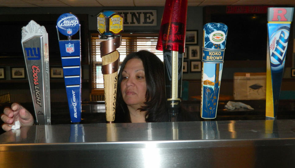 In this March 31, 2014 photo, Gigi Liaguno-Dorr polishes the beer taps at Jakeabob's, the Union Beach N.J. restaurant she used to operate until having to close it the previous weekend. The original Jakeabob's was destroyed in Supoerstorm Sandy, and she moved the business a few blocks inland for 2013. But a continuing inability to get timely rebuilding aid forced her to close the restaurant for good on March 28. The reopening of Jakeabob 's was seen as an inspiration to the still-struggling Raritan Bay community. (AP Photo/Wayne Parry)