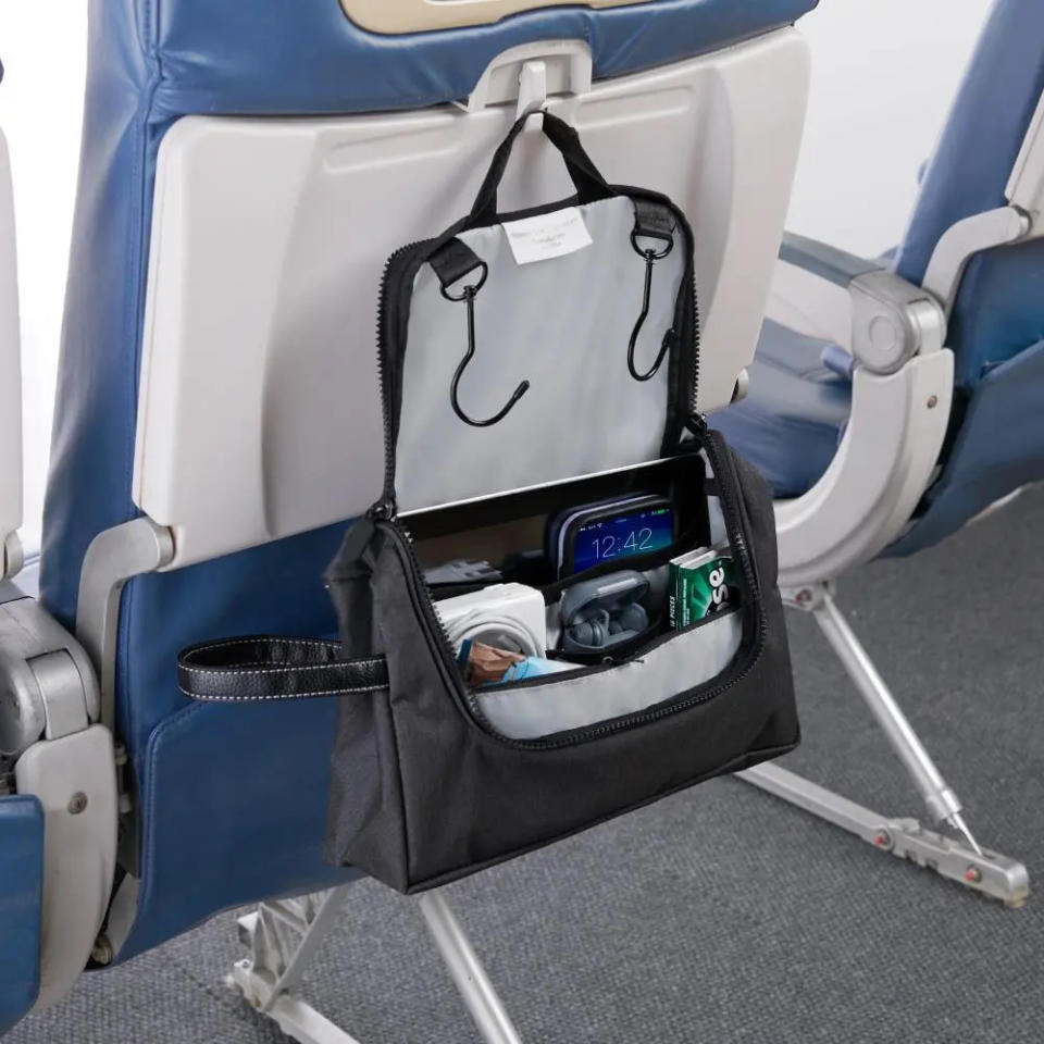 A gray Hammacher Schlemmer in flight hanging organizer hangs from an airplane tray hook