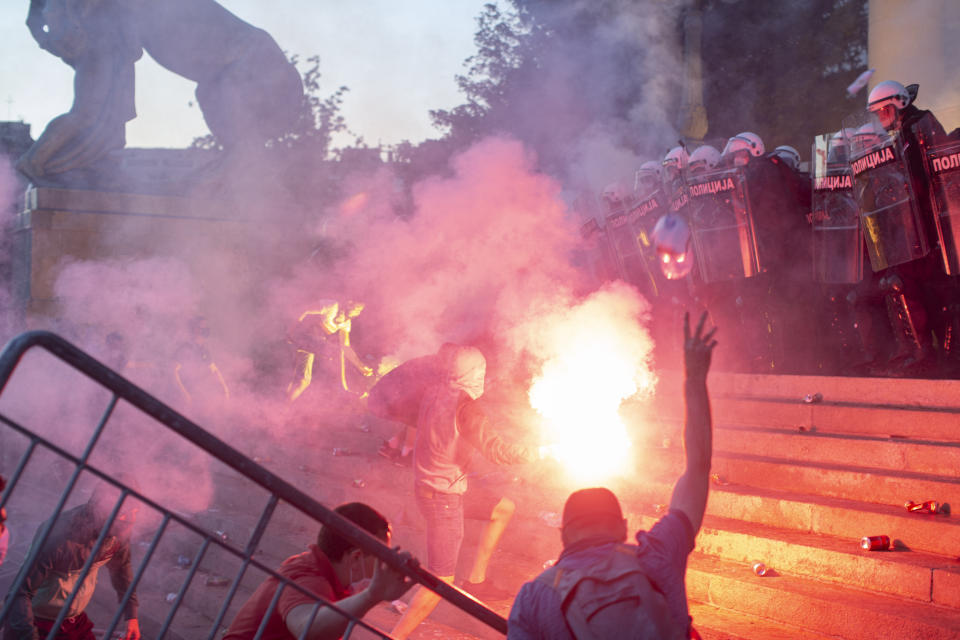 Protesters clash with riot police on the steps of the Serbian parliament in Belgrade, Serbia, Wednesday, July 8, 2020. Police have fired tear gas at protesters in Serbia's capital during the second day of demonstrations against the president's handling of the country's coronavirus outbreak. President Aleksandar Vucic backtracked on his plans to reinstate a coronavirus lockdown in Belgrade this week, but it didn't stop people from firing flares and throwing stones while trying to storm the downtown parliament building. (AP Photo/Marko Drobnjakovic)