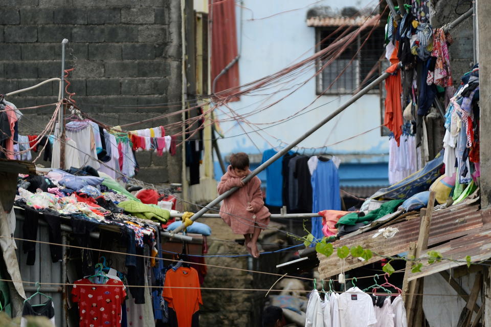 A child sits on a steel pipe in Marikina following the passage of Typhoon Vamco, in Metro Manila, Philippines, November 16, 2020. REUTERS/Lisa Marie David TPX IMAGES OF THE DAY