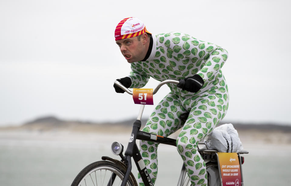 A competitor wearing a onesie with Brussels sprouts battles gale force winds during the Dutch Headwind Cycling Championships on the storm barrier Oosterscheldekering near Neeltje Jans, south-western Netherlands, Sunday, Feb. 9, 2020. (AP Photo/Peter Dejong)