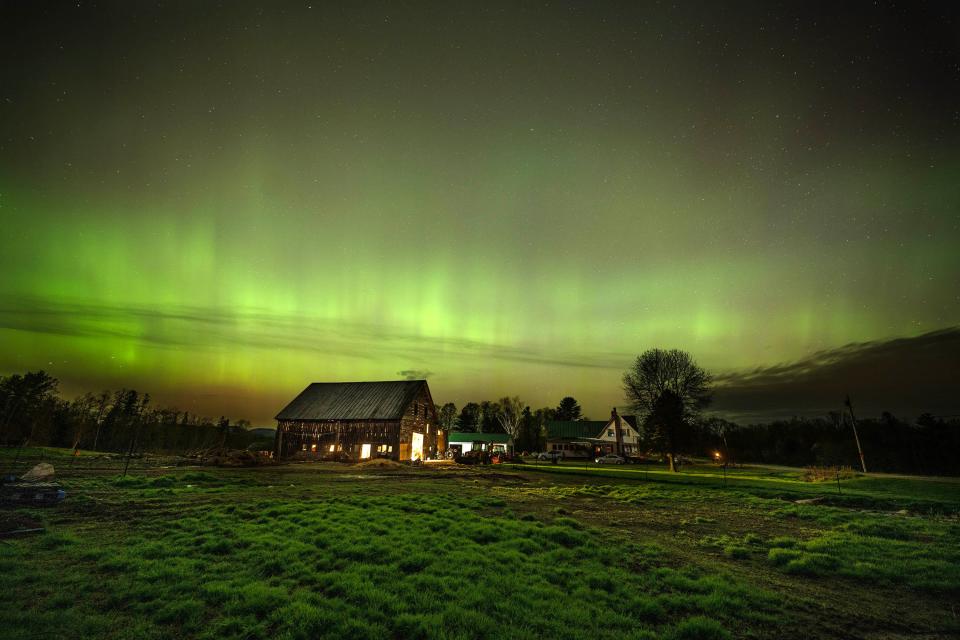 The northern lights fill the sky Saturday, May 11, 2024, with green ribbons of electrical charged particles over the barn and pastures at Greaney's Turkey Farm in Mercer, Maine.