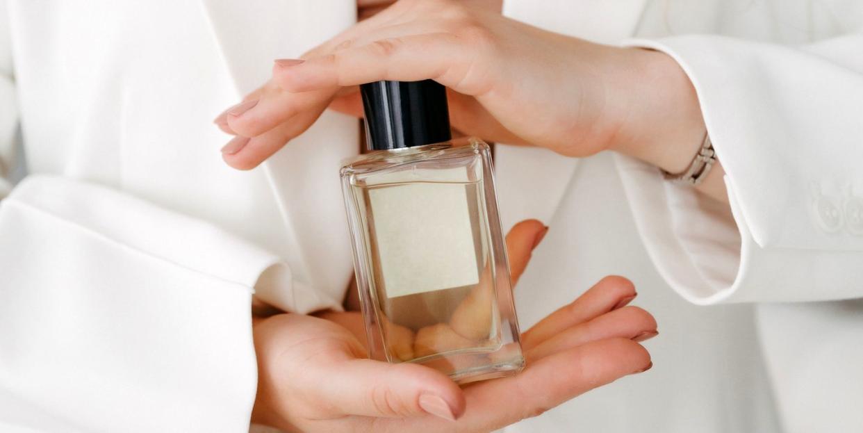 hands of a beautiful young woman with a bottle of floral perfume