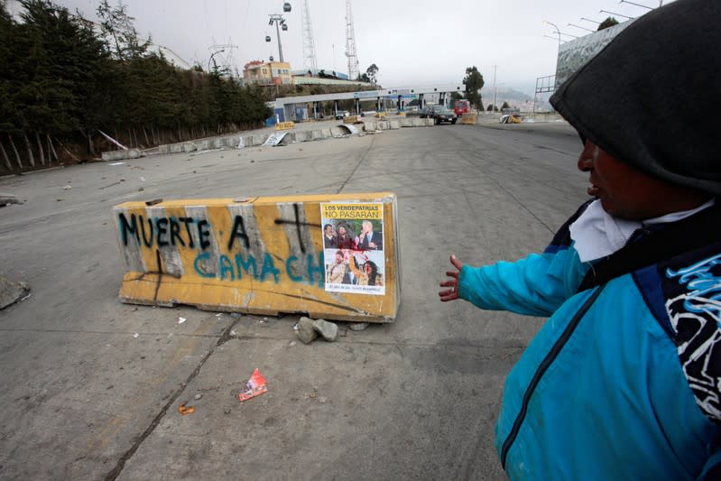 A man points at a roadblock reading "Death to Camacho" after last night's protests, following Bolivia's former president Evo Morales' exit out of the country, in El Alto