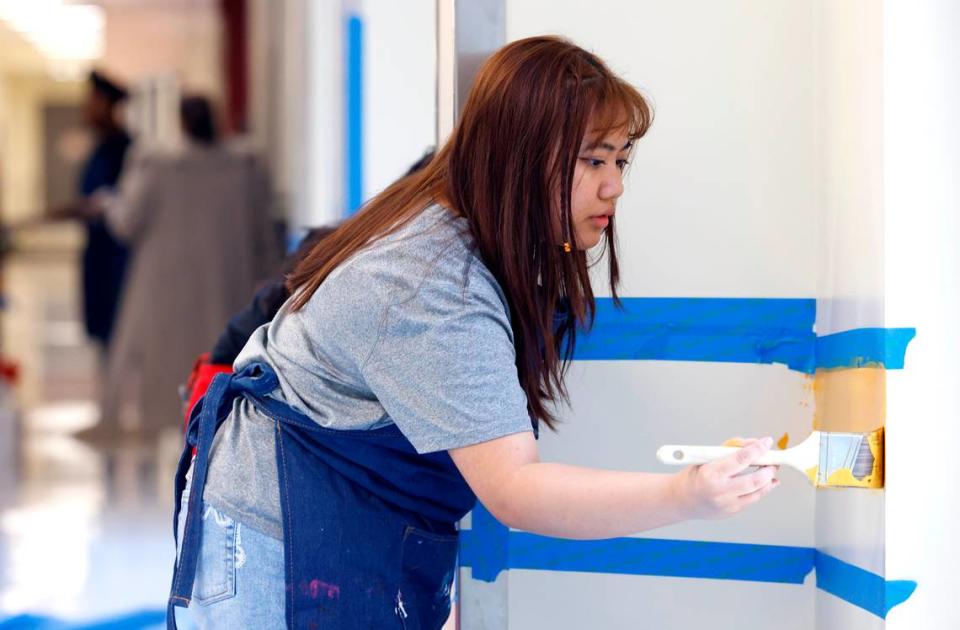 West Charlotte High junior Ain Rocham diligently paints a portion of a mural that she and her fellow students along with local artist Michael Grant are creating in a hallway of the new school on Tuesday, May 2, 2023.