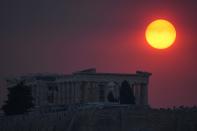 Smoke from a wildfire in the outskirts of the Greek capital covers the sun as it sets over the Parthenon temple atop of the ancient Acropolis ancient in Athens, Tuesday, Aug. 22, 2023. (AP Photo/Thanassis Stavrakis)