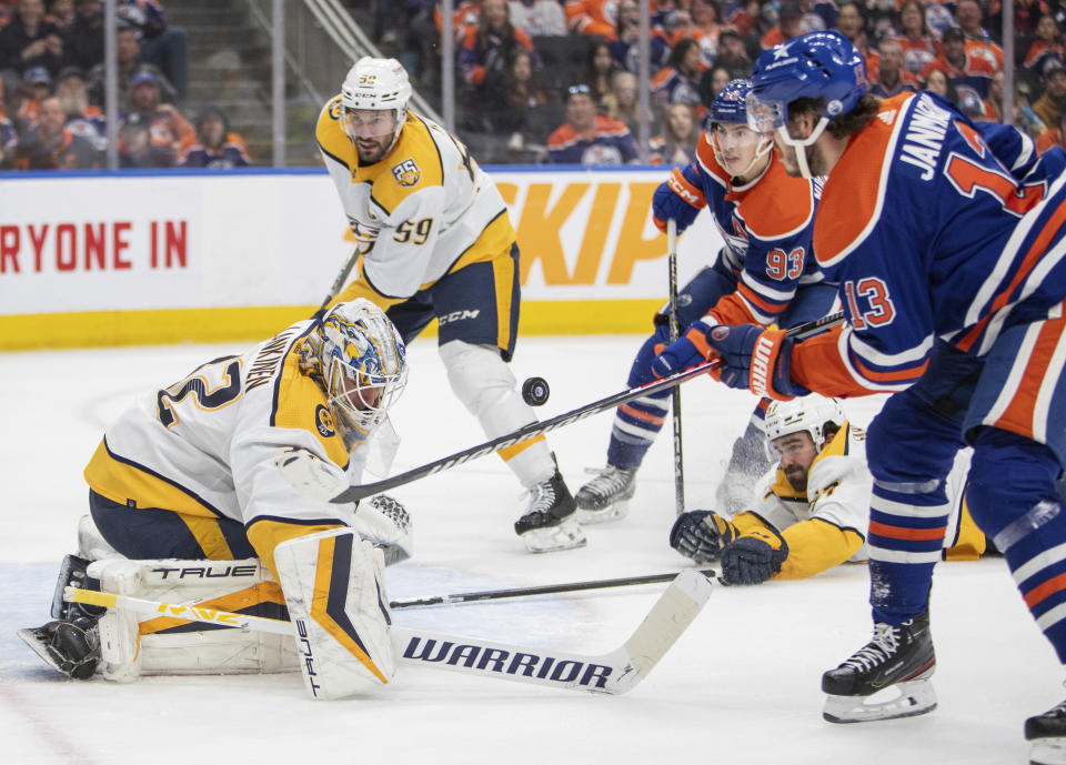 Nashville Predators goalie Kevin Lankinen, front left, watches the puck as teammate Roman Josi (59) and Edmonton Oilers' Ryan Nugent-Hopkins (93) and Mattias Janmark (13) look on during second-period NHL hockey game action in Edmonton, Alberta, Saturday, Jan. 27, 2024. (Amber Bracken/The Canadian Press via AP)