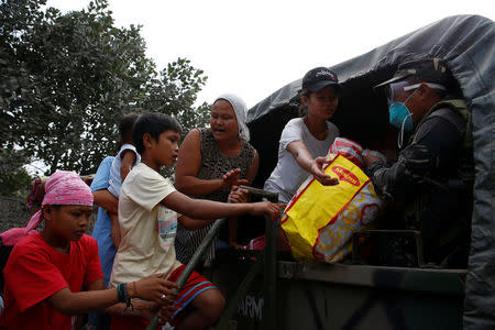 A soldier helps residents as they prepare to depart to an evacuation centre after the Mayon volcano erupted in Guniobatan, Albay Province, Philippines January 23, 2018. REUTERS/Stringer