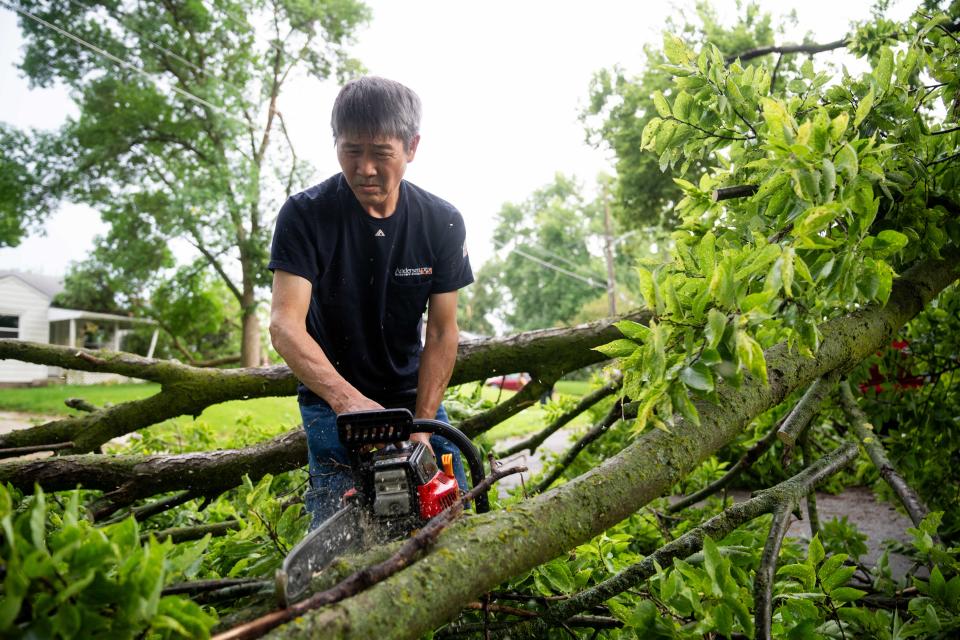Steven Pham clears debris from the roads after a tornado swept through Des Moines on Monday, July 15, 2024, in the Merle Hay neighborhood.