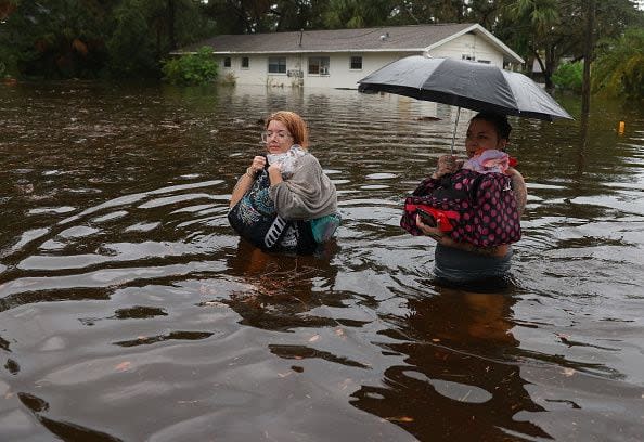 TARPON SPRINGS, FLORIDA - AUGUST 30: Makatla Ritchter (L) and her mother, Keiphra Line wade through flood waters after having to evacuate their home when the flood waters from Hurricane Idalia inundated it on August 30, 2023 in Tarpon Springs, Florida. Hurricane Idalia is hitting the Big Bend area of Florida. (Photo by Joe Raedle/Getty Images)