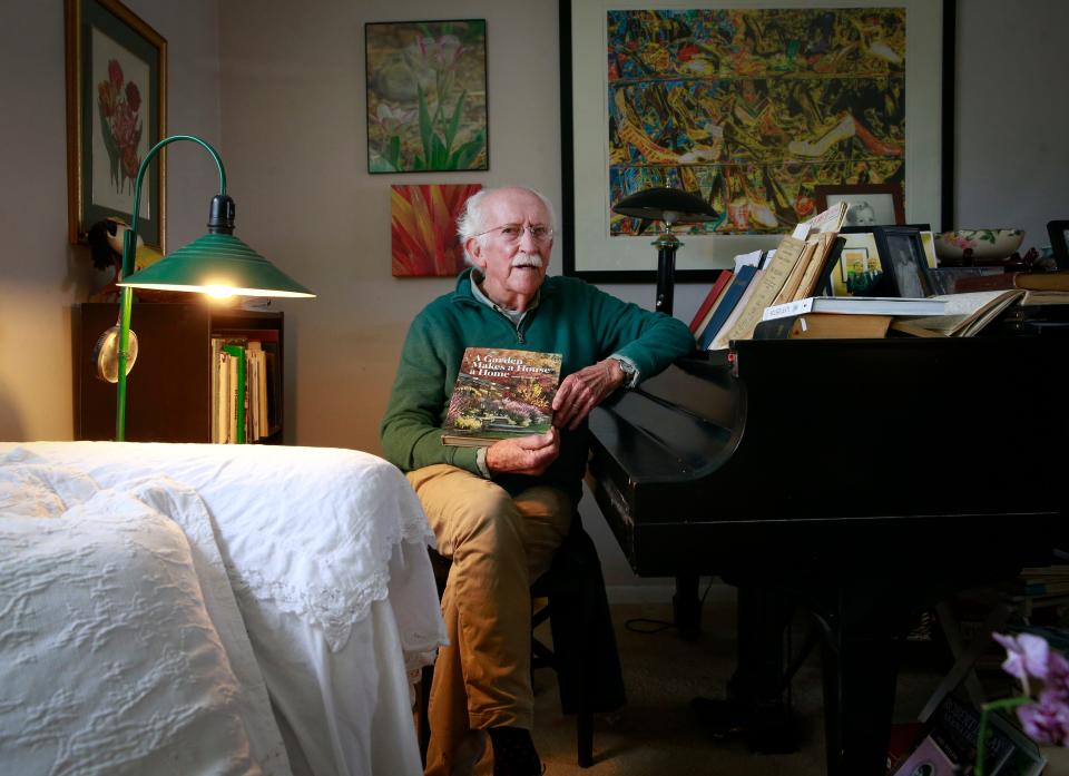 Des Moines gardener and gardening writer Elvin McDonald poses for a photo with one of his books at his home in West Des Moines on Friday, April 22, 2022.