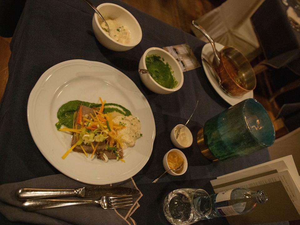 white plate with beef and sauces on a dark table