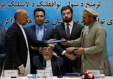 Mohammad Amin Karim (R), representative of Gulbuddin Hekmatyar, and Afghanistan national security adviser Mohammad Hanif Atmar (L) hold a document after signing a peace deal in Kabul, Afghanistan, September 22, 2016. REUTERS/Omar Sobhani