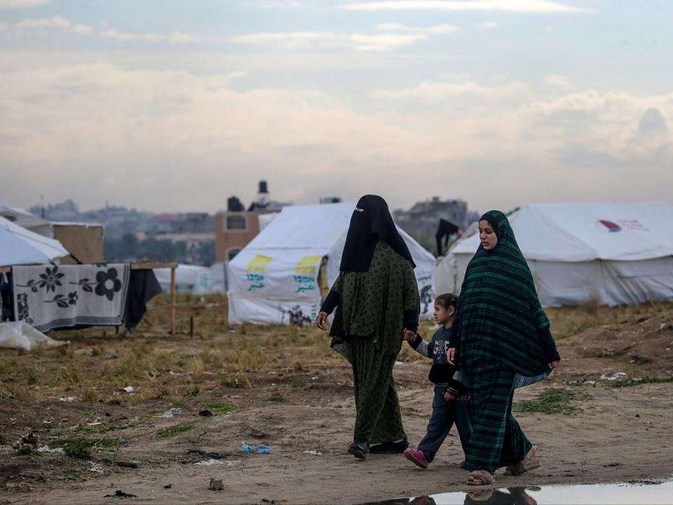 Displaced Palestinian women from Rafah walk next to their shelters in Deir Al Balah, southern Gaza, in February 2024 (EPA/Mohammed Saber)